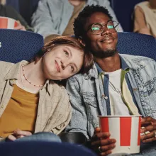 A happy couple eating popcorn at a movie theater